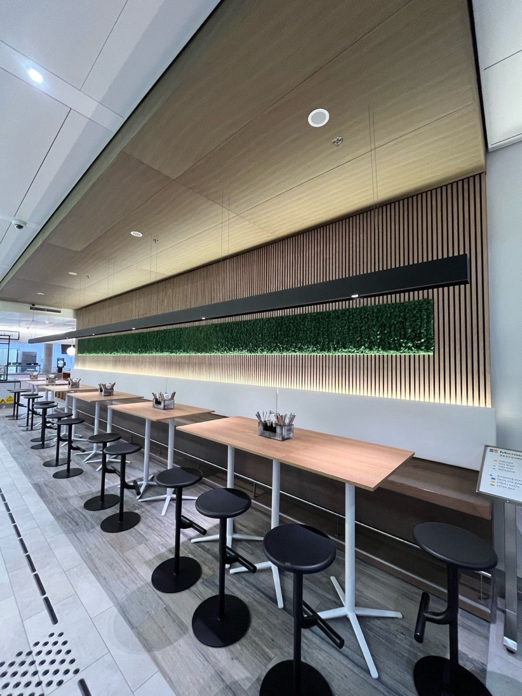 Microsoft HQ München — Mitarbeiter-Restaurant mit Eichen-Lamellenwand, Moos-Paneel und Stehtischen